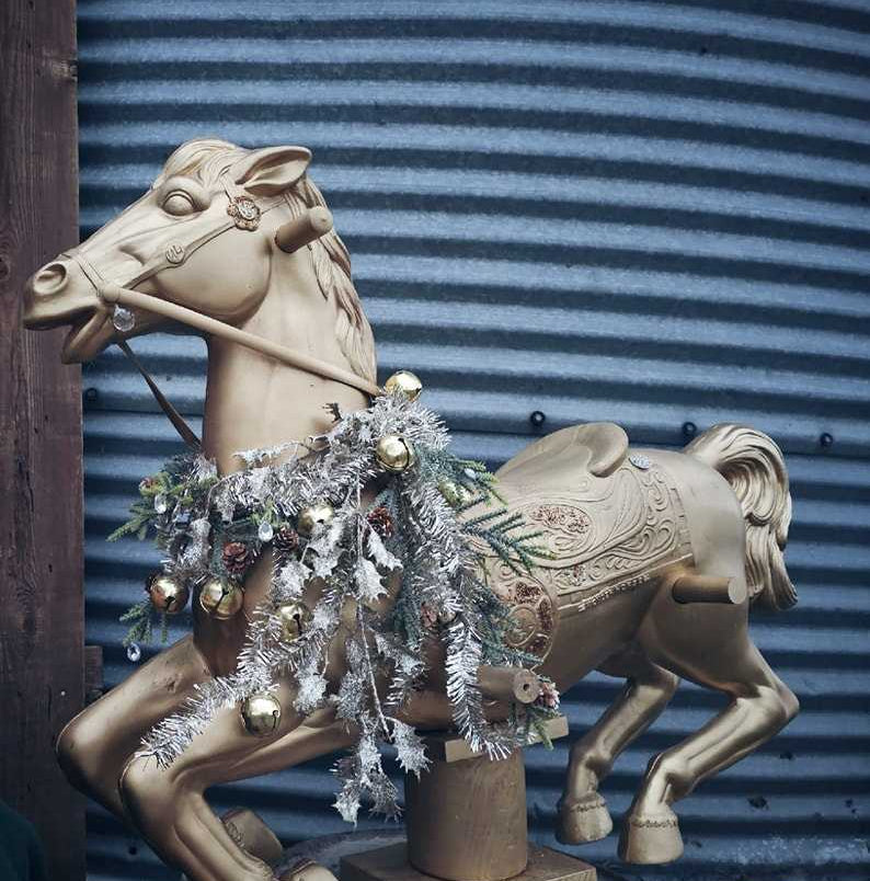 Decorative horse sculpture with tinsel against a corrugated metal background