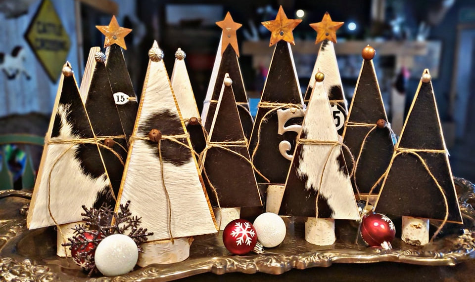 Decorative wooden cowhide trees with stars and holiday ornaments on a metallic tray.