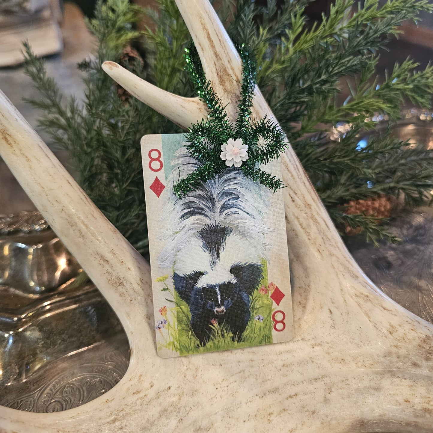 Vintage style skunk playing card Christmas ornament hanging on an antler