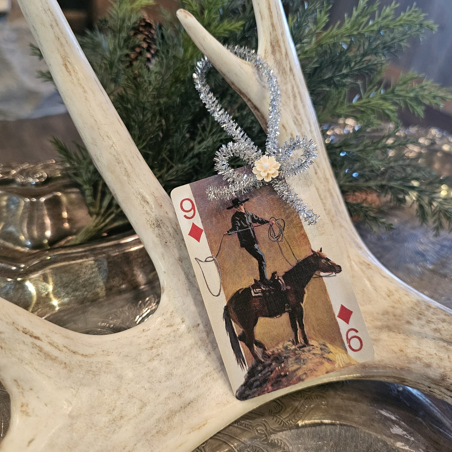 Vintage style cowboy and horse playing card Christmas ornament hanging on an antler