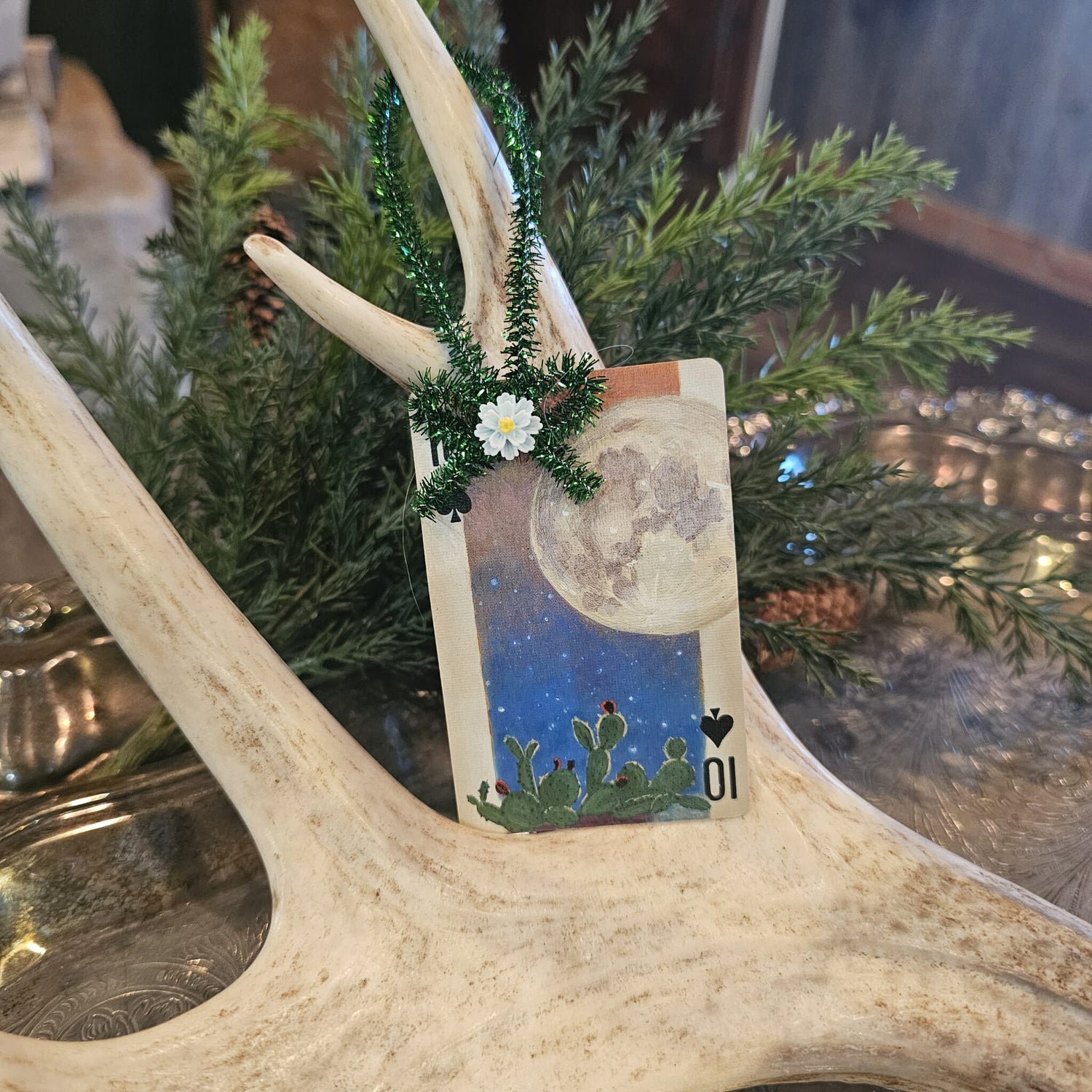 Vintage style cactus and moon playing card Christmas ornament hanging on an antler