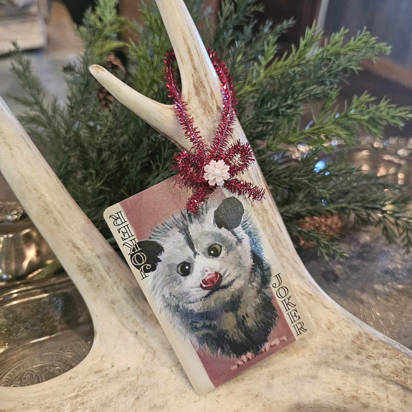 Vintage style possum playing card Christmas ornament hanging on an antler