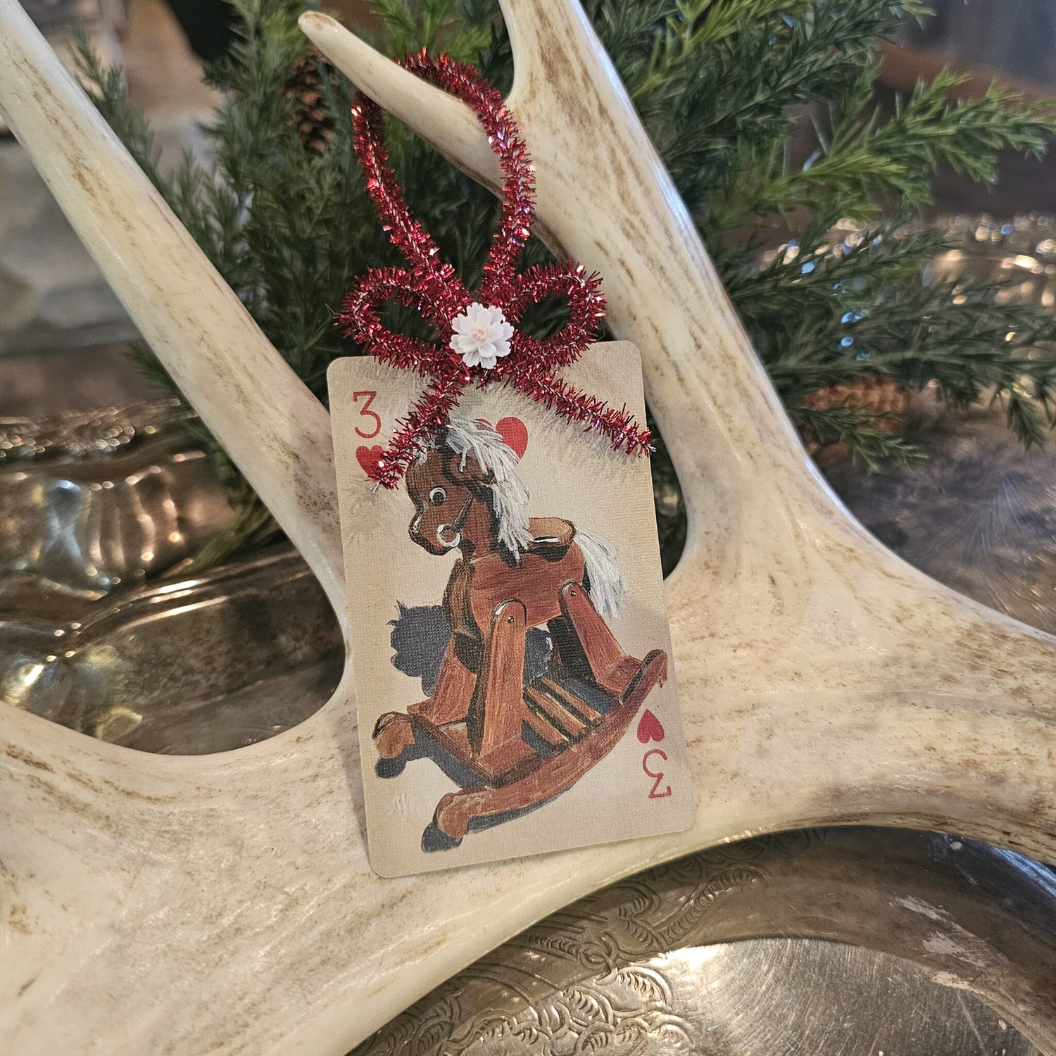 Vintage style rocking horse playing card Christmas ornament hanging on an antler