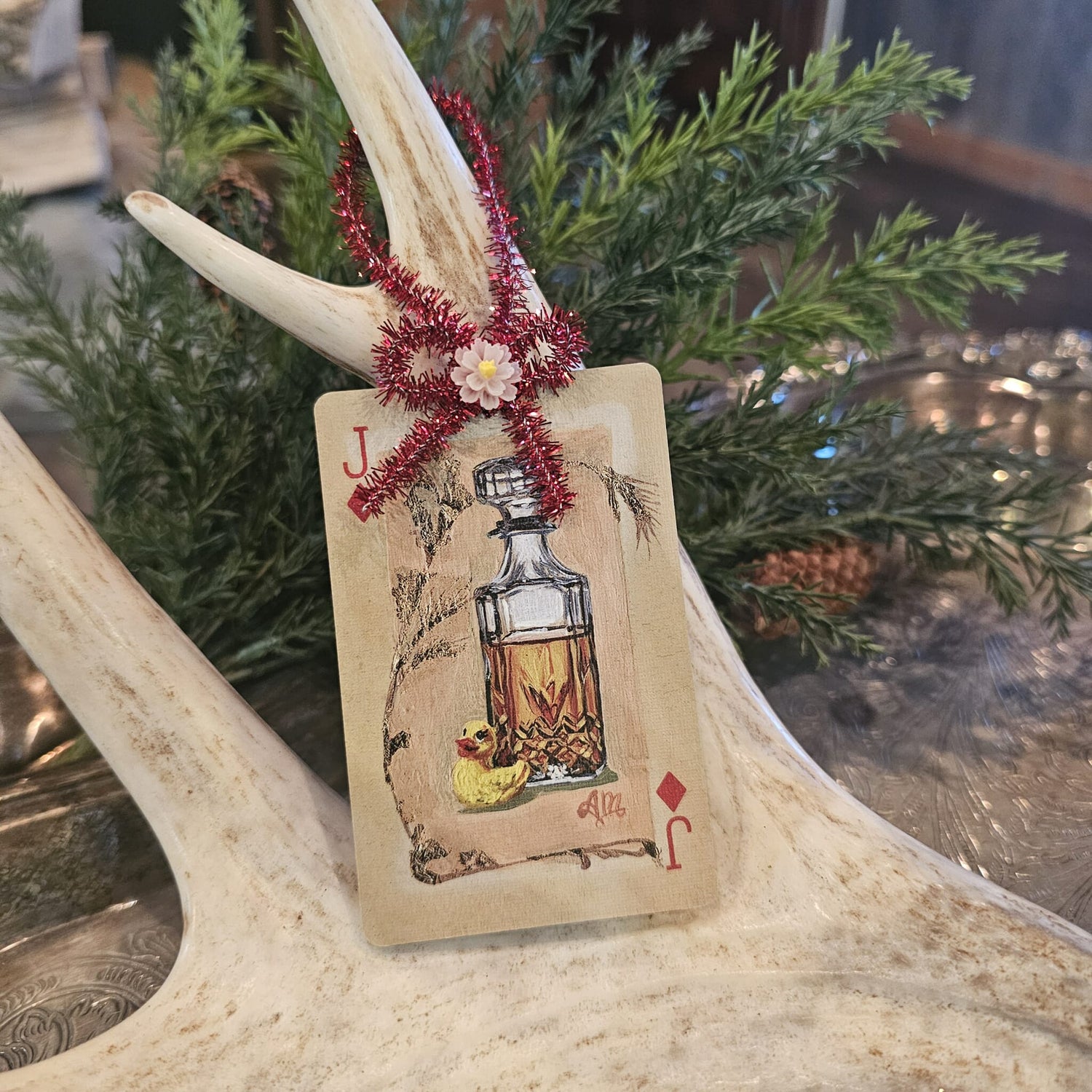 Vintage style glass bottle and toy duck playing card Christmas ornament hanging on an antler