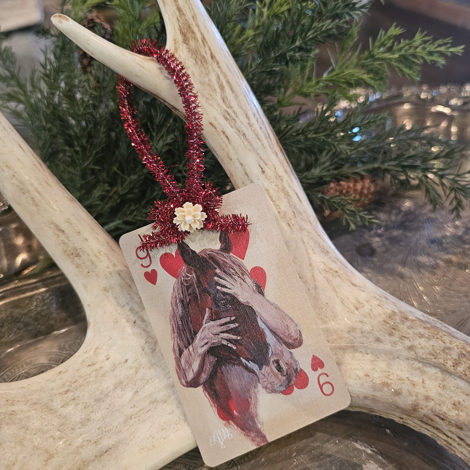 Vintage style horse being hugged playing card Christmas ornament hanging on an antler