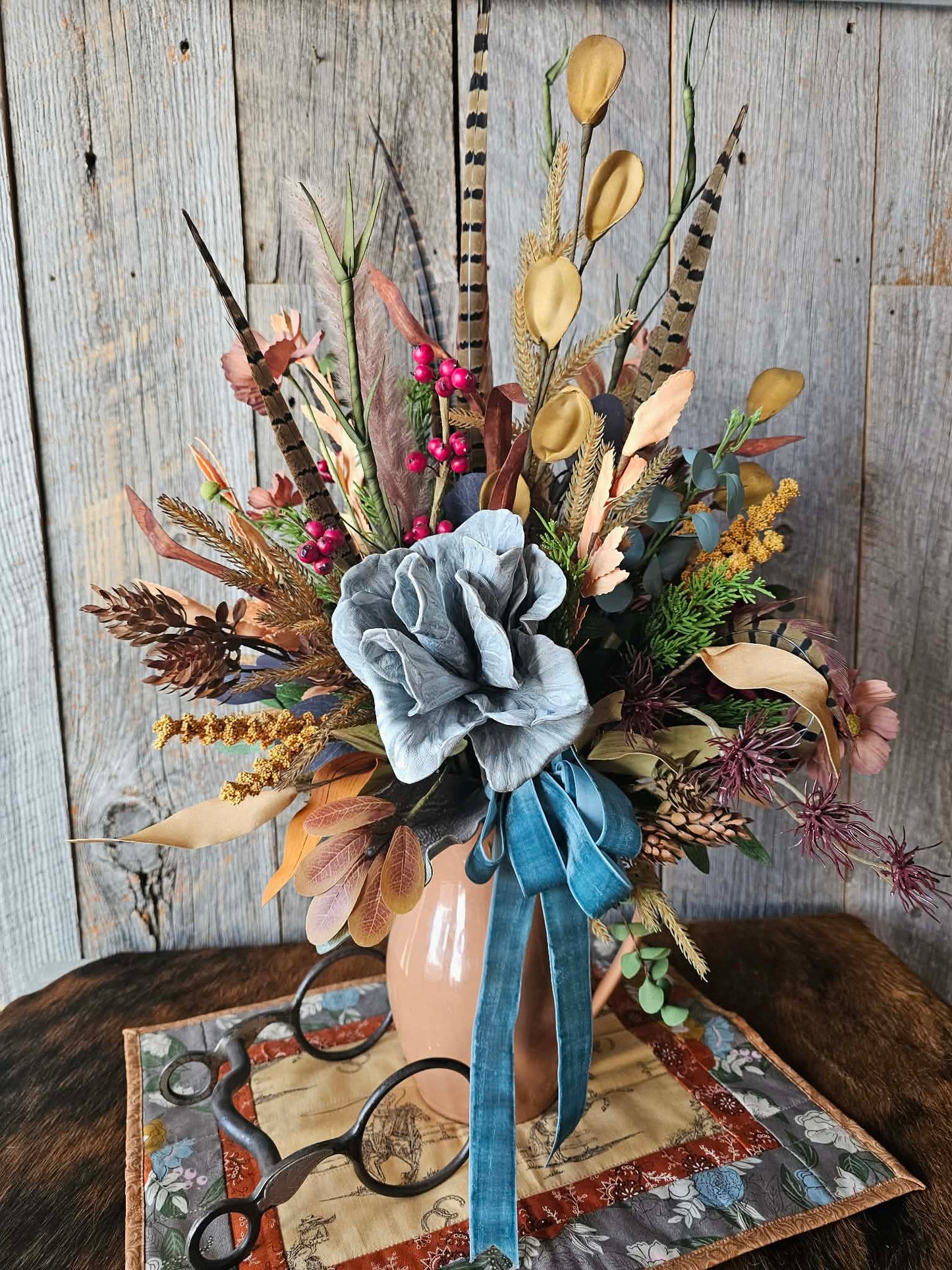 Decorative floral arrangement with a blue ribbon against a wooden background