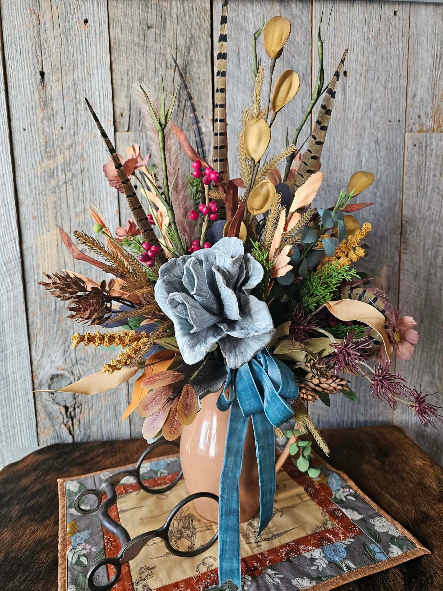 Decorative floral arrangement with a blue ribbon against a wooden background