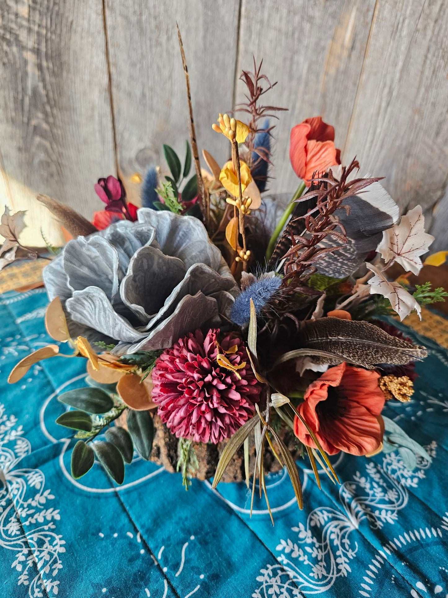 Colorful flower arrangement on a blue patterned fabric with wooden background