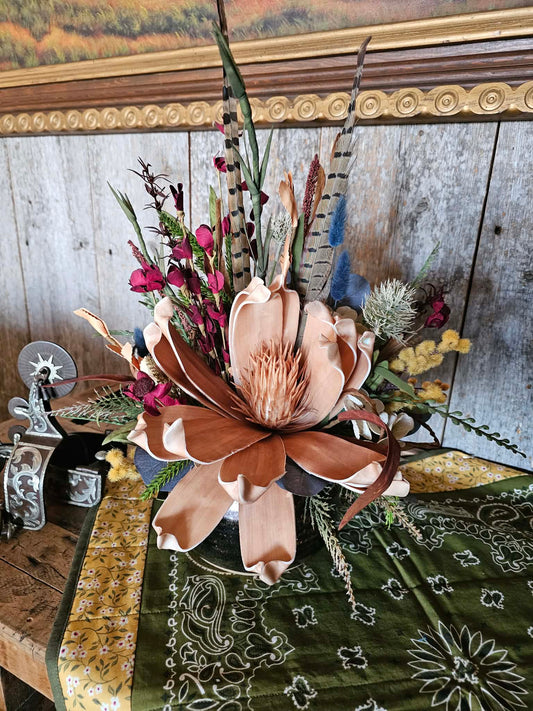 Decorative floral arrangement with feathers on a rustic wooden surface