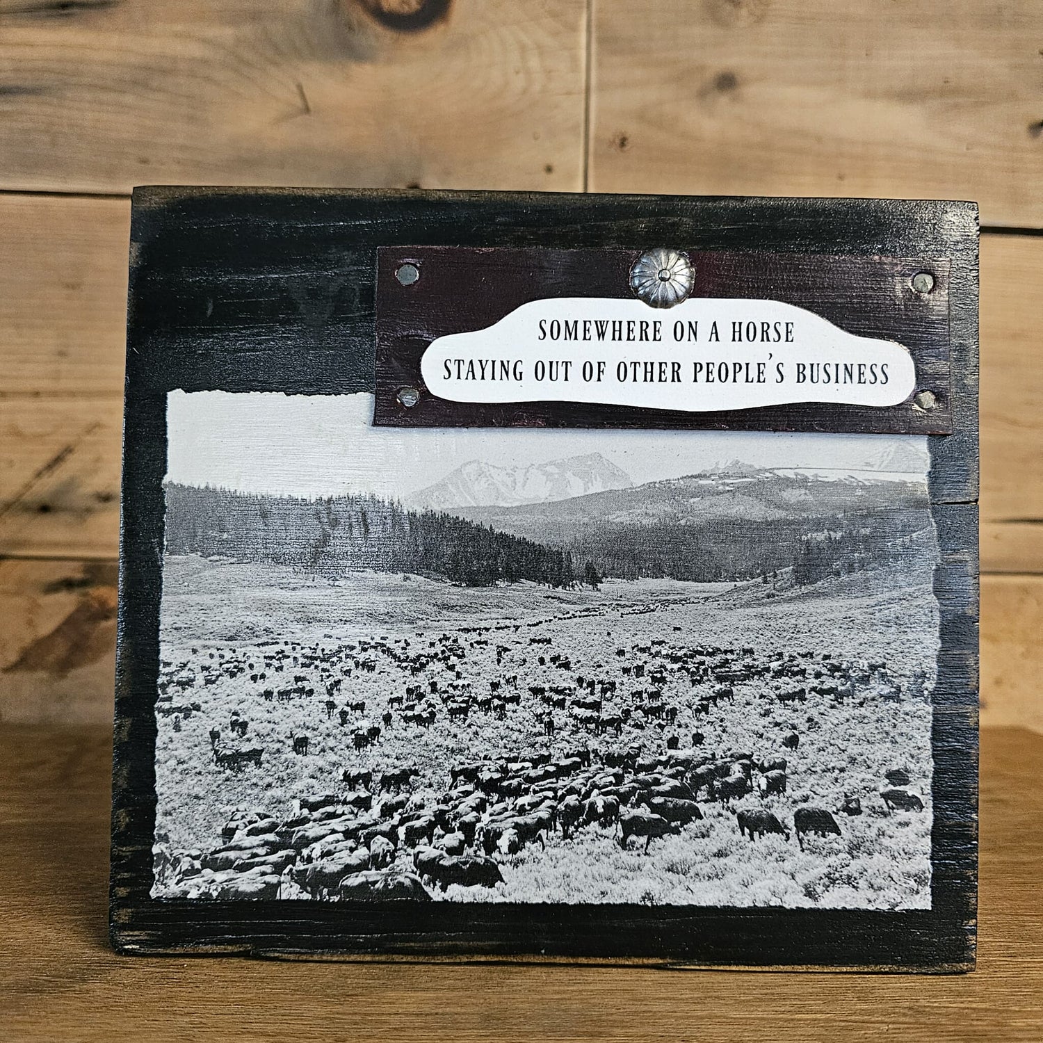 Wooden plaque with a black and white photo of a landscape and text on a wooden surface